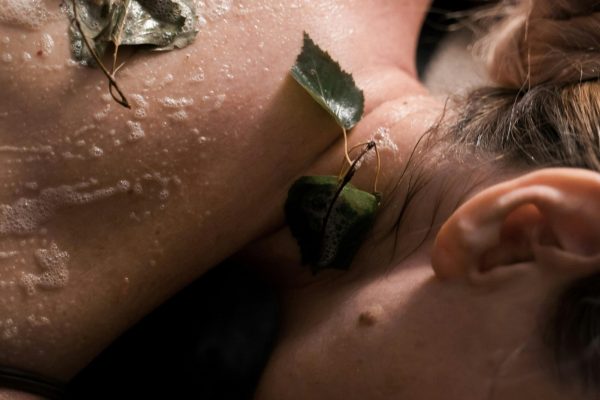 Close-up of a woman enjoying a relaxing spa treatment with natural leaves and exfoliation.